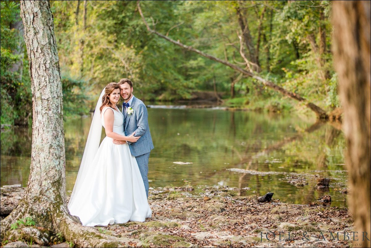 Outdoor bride and groom portrait by a stream
